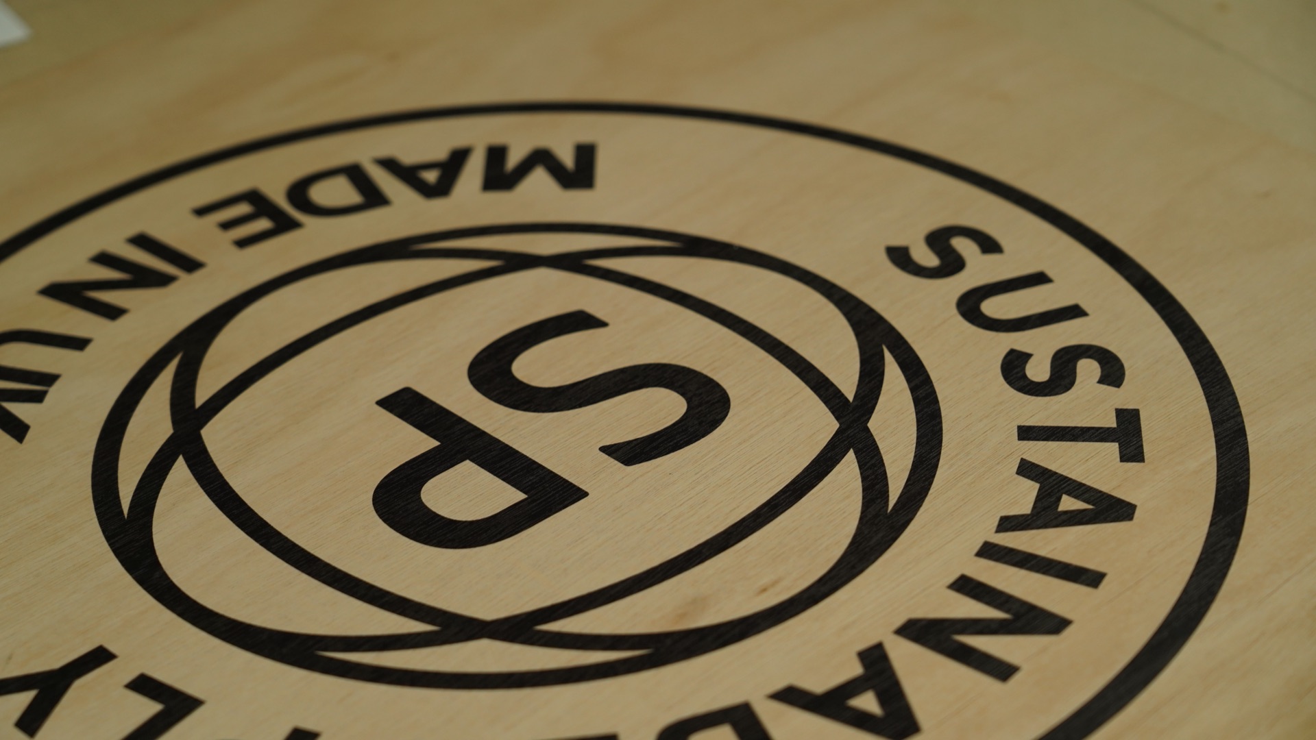Sustainable Ply roundel printed in dark ink on a maple plywood panel face, Made in UK stamp detail
