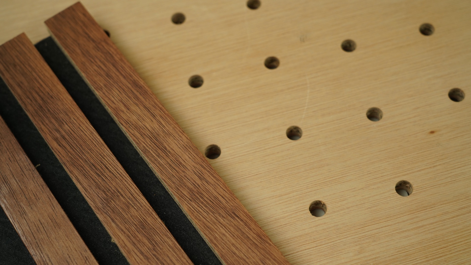 Perforated Sustainable Ply acoustic panel with timber batten finish samples laid across the corner