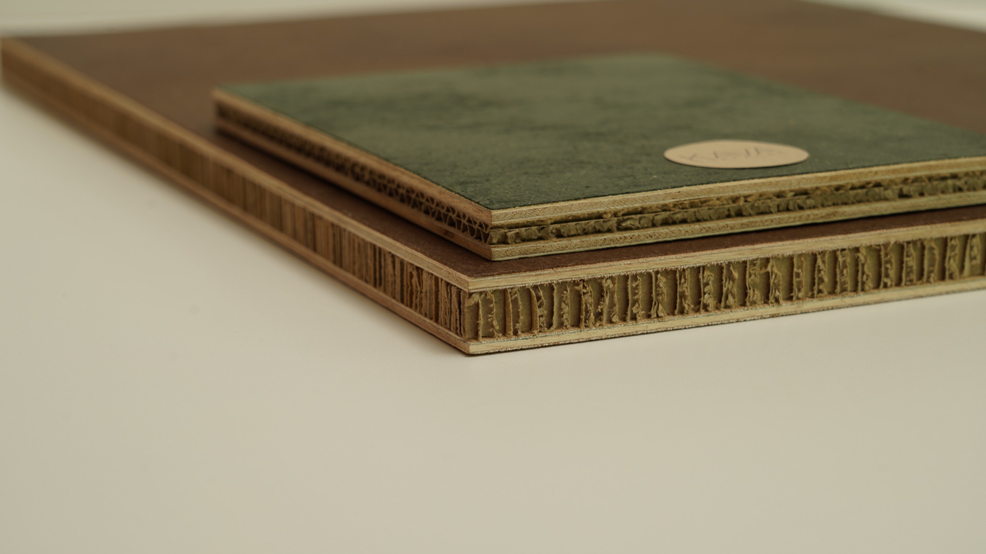 Stacked Sustainable Ply panels with green and brown faces, cardboard cores visible at the edge