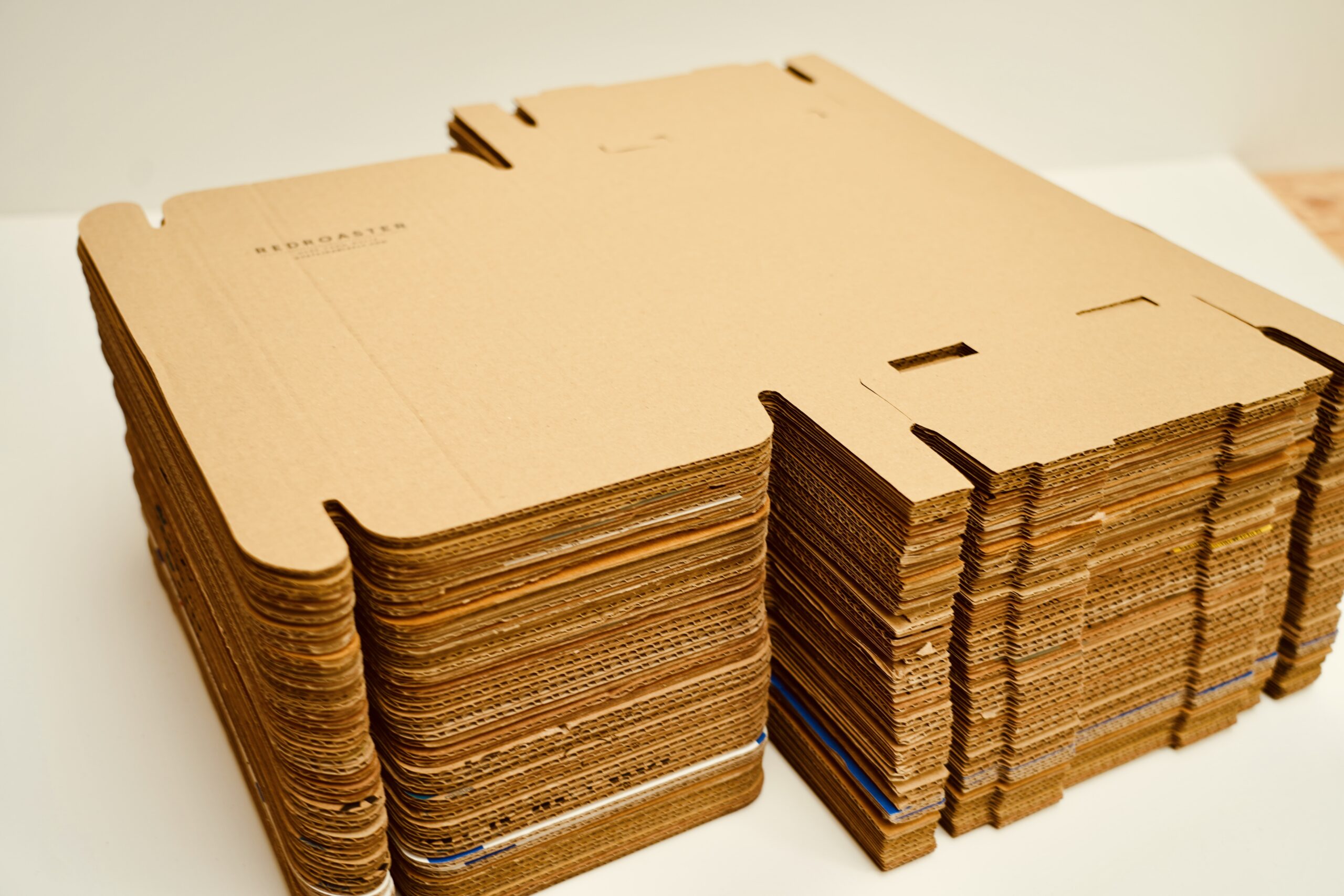Stacks of flat-packed upcycled corrugated cardboard boxes, die-cut and ready for assembly.