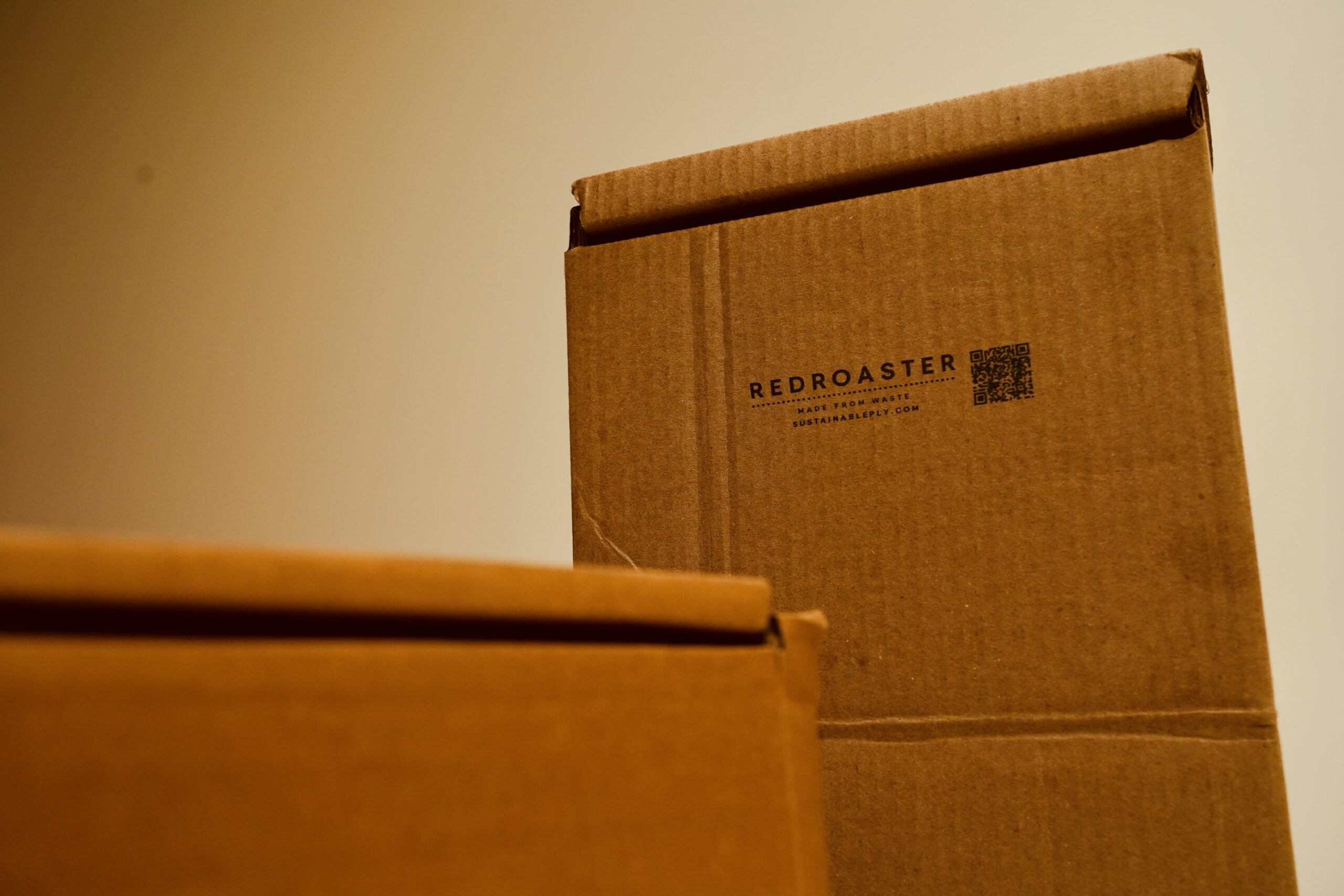 Reusable cardboard box branded for Redroaster with a ‘Made From Waste’ stamp, showing Sustainable Ply’s upcycled packaging.